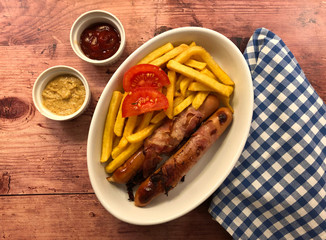 Bacon wrapped sausages with french fries and dip. Hearty meal concept.