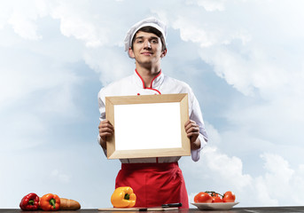 Young male chef standing near cooking table
