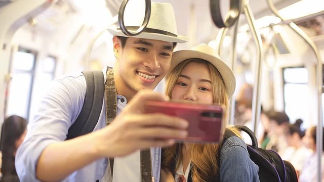 Portrait of attractive smiling Asian  girl in train using smartphone chatting with friends woman hand internet technology cellphone city .