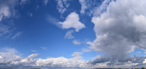 September is the autumn sky. White aerial clouds on a blue sky, panoramic photo.