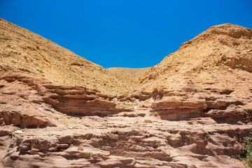 Obraz premium Israeli desert scenery dry landscape sand stone rocks wallpaper background view with empty vivid blue sky 