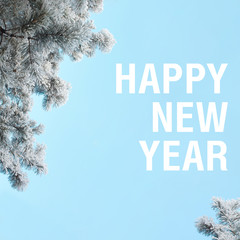 Happy New Year words winter square aspect ratio orientation on pastel sky blue colors. Snow covered...