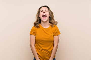 Young blonde girl over isolated background shouting to the front with mouth wide open