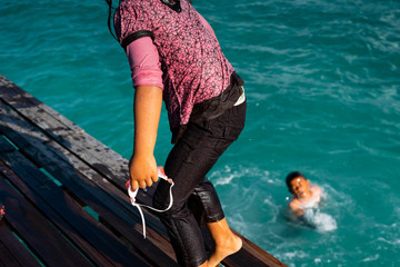 Semporna, Malaysia - November 26, 2019 : Kids climb up the ladder on a pier, after having jumped...