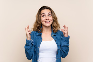 Obraz premium Young blonde woman over isolated background with fingers crossing