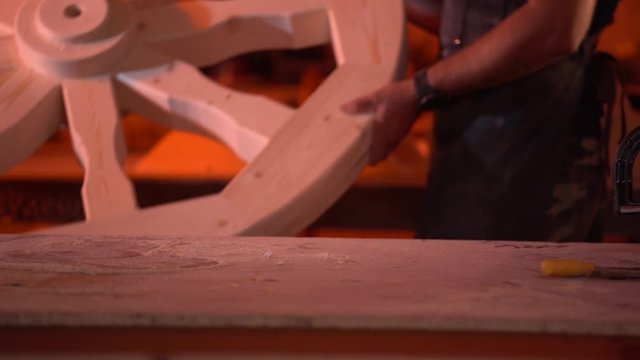 two joiners lift the wooden wheel after processing and carry aside