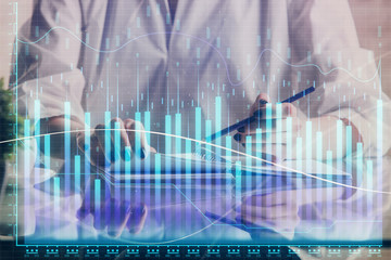 Financial forex graph drawn over hands taking notes background. Concept of research. Double exposure