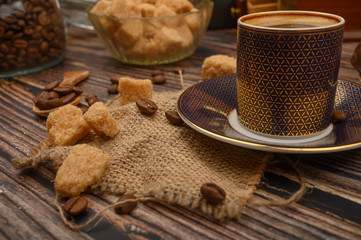 Coffee Cup, coffee beans, brown sugar on wooden background. Close up.