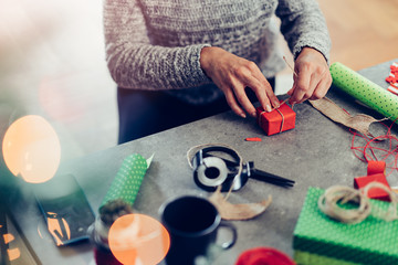 Woman sitting by the table and wrapping Christmas presents