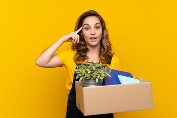Young blonde girl making a move while picking up a box full of things intending to realizes the...