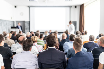 I have a question. Group of business people sitting at the chairs in conference hall. Businessman...