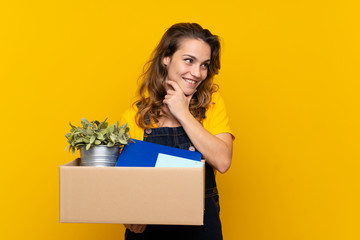 Young blonde girl making a move while picking up a box full of things looking side