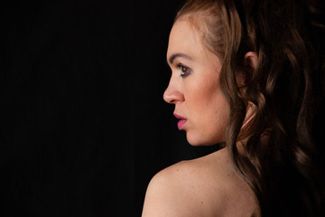 portrait of a sexy girl with long hair in a short dress with an open back on a black background