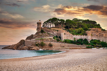 The Spanish city of Tossa de Mar located in Costa Brava is a coastal region of Catalonia. Beautiful sunset sky, an ancient cliff fort, sandy beach and the Mediterranean Sea. - 306535051