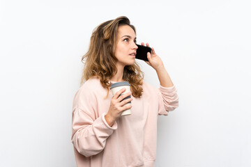 Young blonde woman holding coffee to take away and a mobile