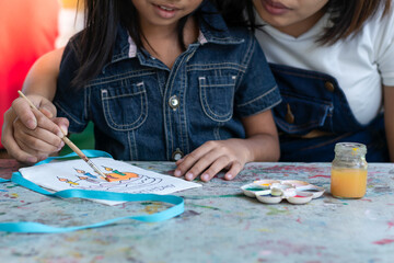 Fototapeta premium The mother and child are involved in creating watercolor artwork on cloth bags.