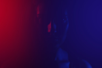 portrait of a girl in the dark. silhouette of a girl in the light of colored lamps in red and blue.