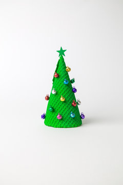 Green ice cream cone in form of Christmas tree decorated with colorful baubles and star on white background minimal creative holiday and food concept.