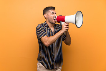 Handsome man with beard over isolated background shouting through a megaphone