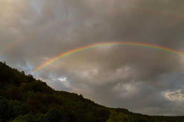 Fototapeta na wymiar Rainbow profiled on storm clouds, in the mountais
