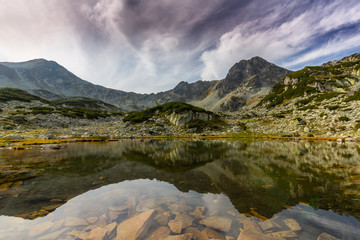 Marvelous glacier lake in the Romanian Alps, in summer, and dramatic storm clouds