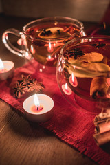 Apple Cider Drink, Juice, Punch, Tea with Spices, Cinnamon sticks, star anise and fresh Apples lit by candlelight on a wooden background. Hot drink for Autumn and Winter evenings. Close up. .
