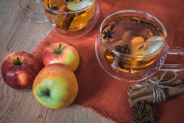 Apple Cider Drink, Juice, Punch, Tea with Spices, Cinnamon sticks, star anise and fresh Apples on a wooden background. Hot drink for Autumn and Winter evenings. Close up. Seasonal mulled drink.