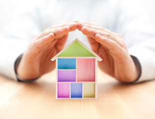 Colorful wooden house protected by hands