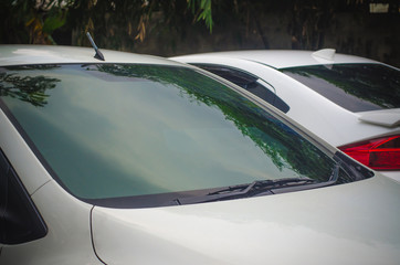 Fototapeta na wymiar Section of the front of a white vehicle and its front windscreen bonnet and wipers.