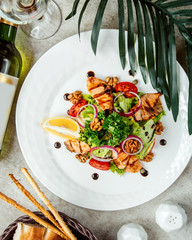 mixed salad with lemon slices, walnuts and fried meat