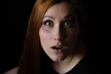 Fototapeta premium portrait of a young woman on a black background. Surprise on the face. female emotions