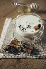 Glass cup of traditional indian masala chai tea. Indian masala chai tea - spiced tea with milk on rustic wooden background, selective focus, copy space. Close up.