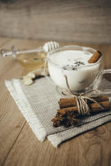 Glass cup of traditional indian masala chai tea. Indian masala chai tea - spiced tea with milk on rustic wooden background, selective focus, copy space. Close up.
