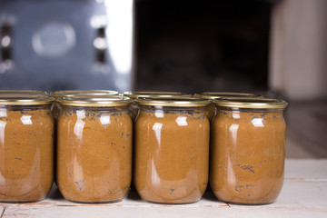 Cans of canned food are on the table, behind a wood-burning stove. Photo recipe
