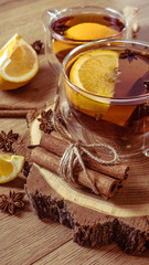 Orange flavored tea with cinnamon and cardamom in glasses, orange and cinnamon sticks on a wooden table. Mulled wine and spices on wooden background. Selective focus. Close up.