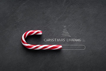 Christmas loading Concept - Candy cane on blackboard with christmas tree