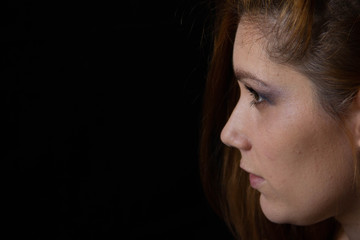 portrait of a young beautiful woman against black background. female face profile