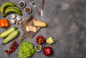 Ingredients for cooking healthy vegetarian food with a board on a dark background. Diet concept. Top view with place for text.