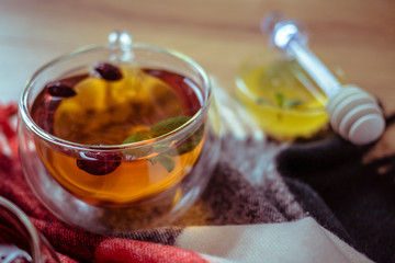 Dried rose-hip berries and rosehip tea on the rustic table. In a glass cup tea of rosehip and leaves mint. Medicinal plants and herbs composition. Autumn and winter season background. Close up