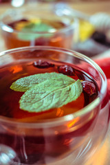Dried rose-hip berries and rosehip tea on the rustic table. In a glass cups tea of rosehip and leaves mint. Medicinal plants and herbs composition. Autumn and winter season background. Close up