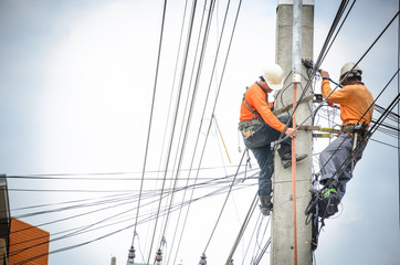 Electricians are climbing on electric poles to install and repair power lines.