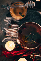 Black cup tea with dried rosehip and fresh leaves mint on the background of scattered dried rose hips and wax candles. Selective focus. Close up. Autumn and winter background.
