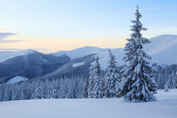 Amazing winter sunrise. Sun rays lighten up the sky and horizon. Landscape of high mountains....