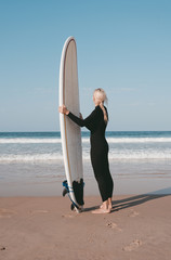 Fototapeta na wymiar A girl staying with a surfboard on the beach of the Atlantic ocean Peniche Portugal