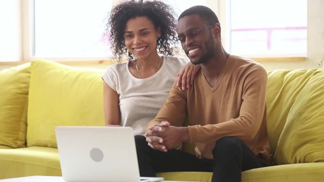 Happy african young couple talking to webcam making video call