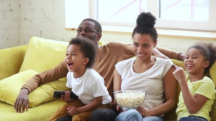 Happy african american family mom dad and kids watching tv - Powered by Adobe