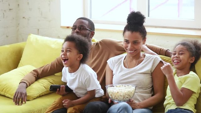Happy african american family mom dad and kids watching tv