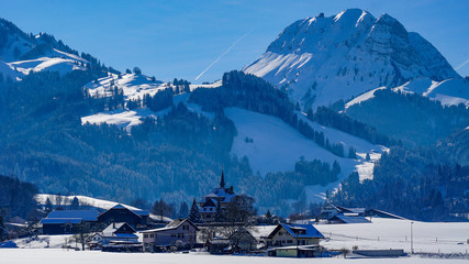 ch&acirc;teau de Gruy&egrave;res sur sa colline en suisse dans un paysage enneig&eacute; et de la for&ecirc;t et le Mol&eacute;son et le village de Gruy&egrave;res &agrave; l'avant
