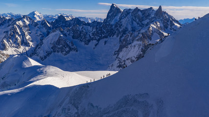 Cordée d'alpinistes au Mont-Blanc dans un décors enneigé avec des montagnes dans le fond