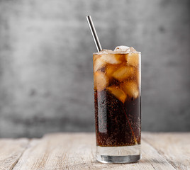 close-up glass with soda and ice, drops of water, metal straw, on a gray background